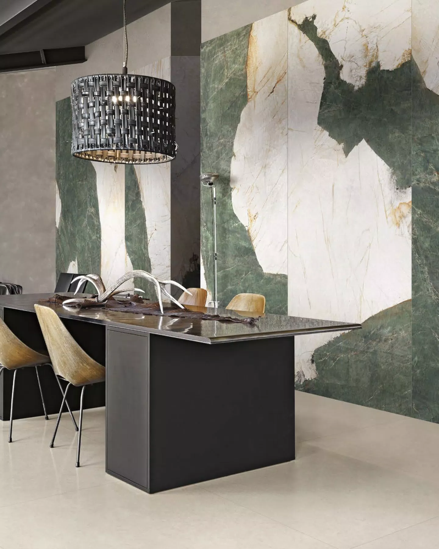A modern dining area featuring a solid beige floor and a bold white and green marble look gauged porcelain panel.